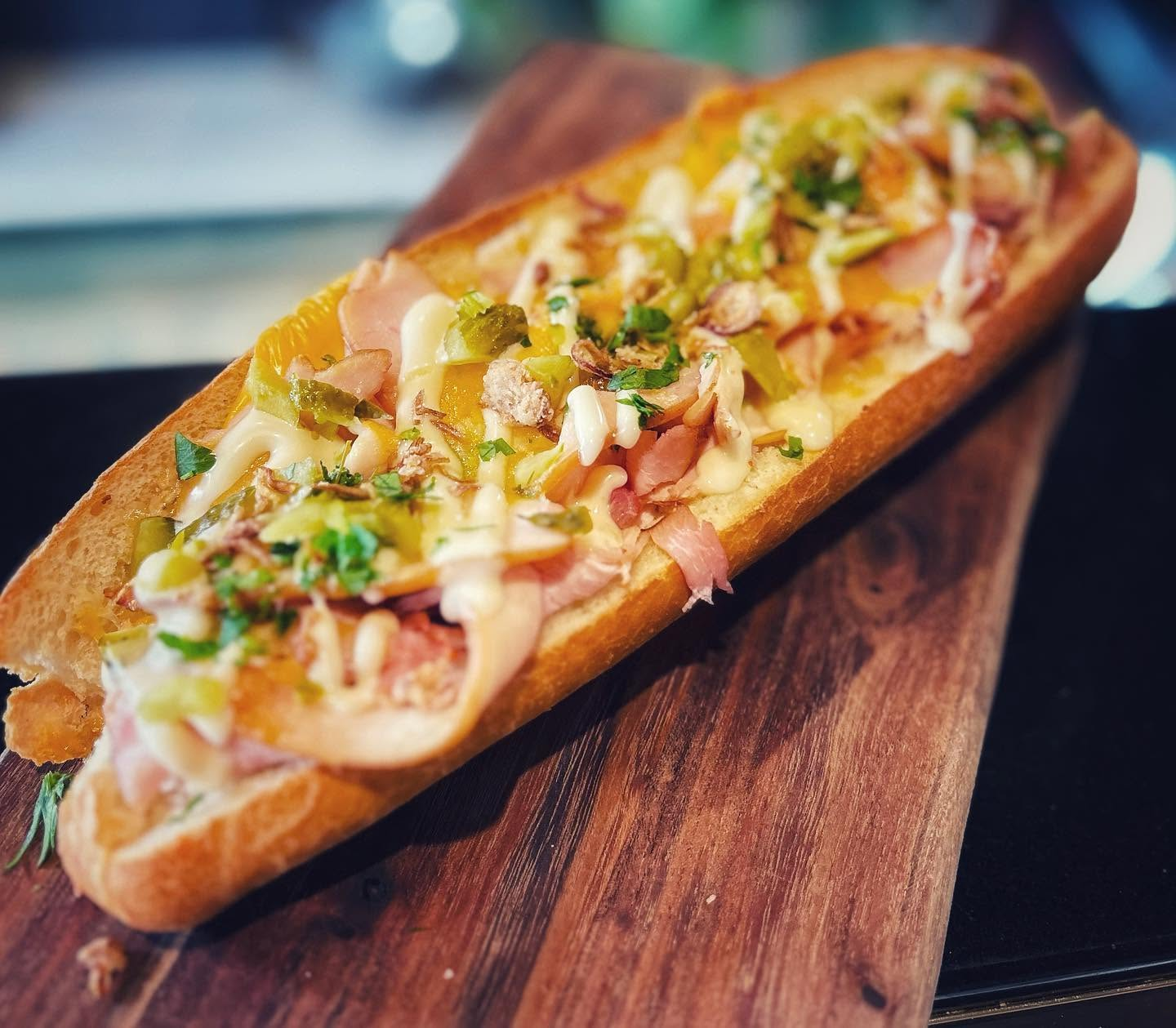 Loaded sub sandwich with premium smoked meats and toppings on a wooden board