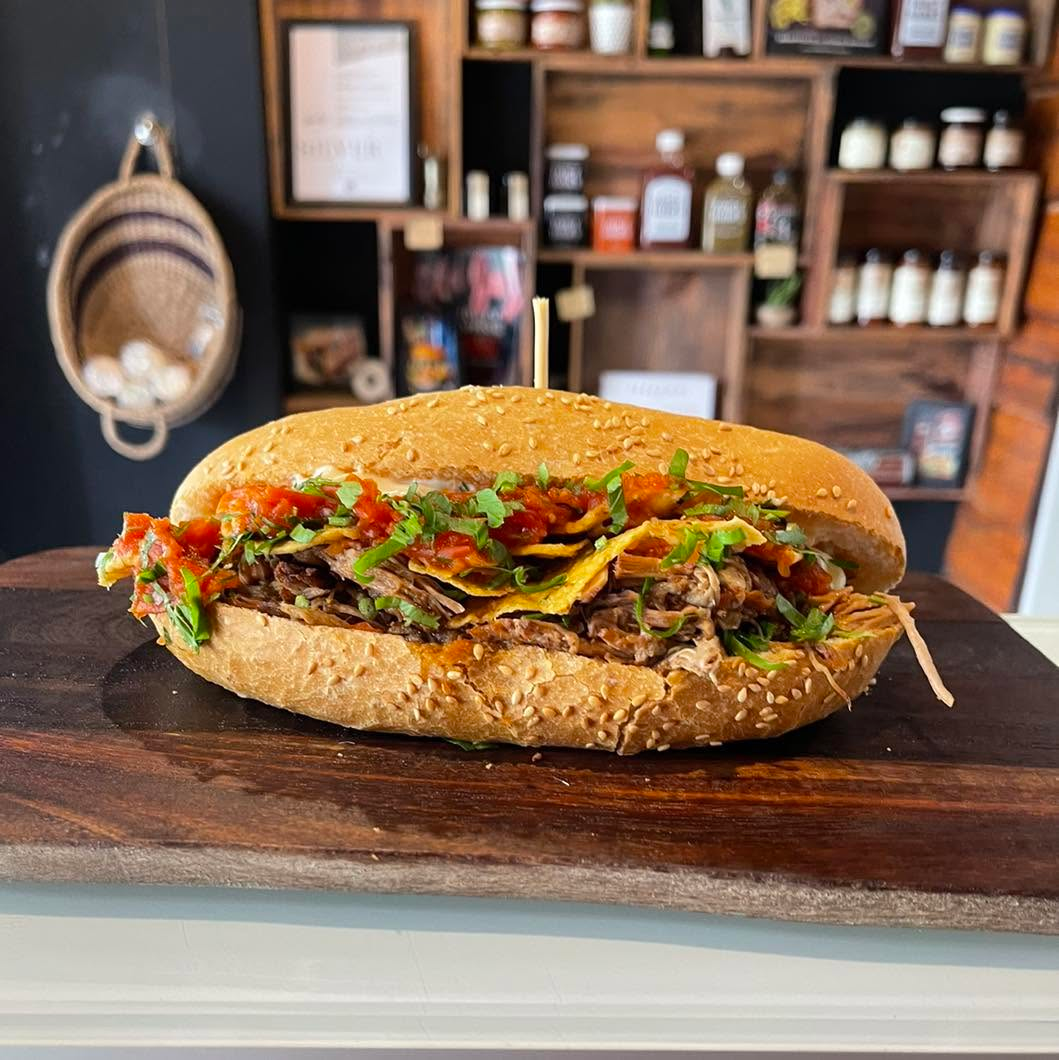 Loaded brisket sandwich on a sesame roll with fresh salsa and herbs